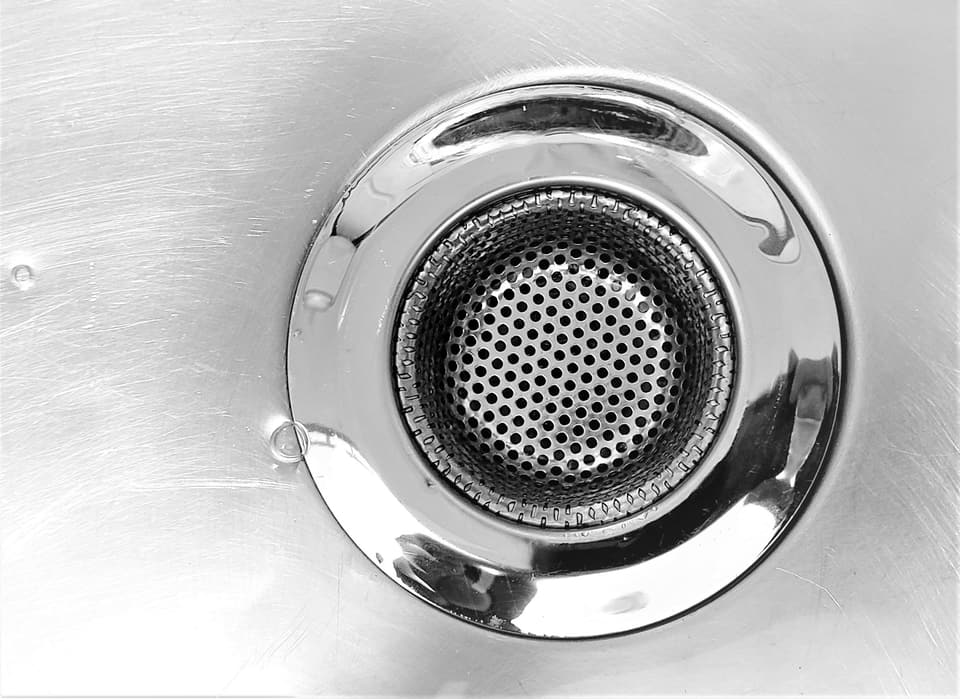 A stainless steel strainer in a kitchen sink drain