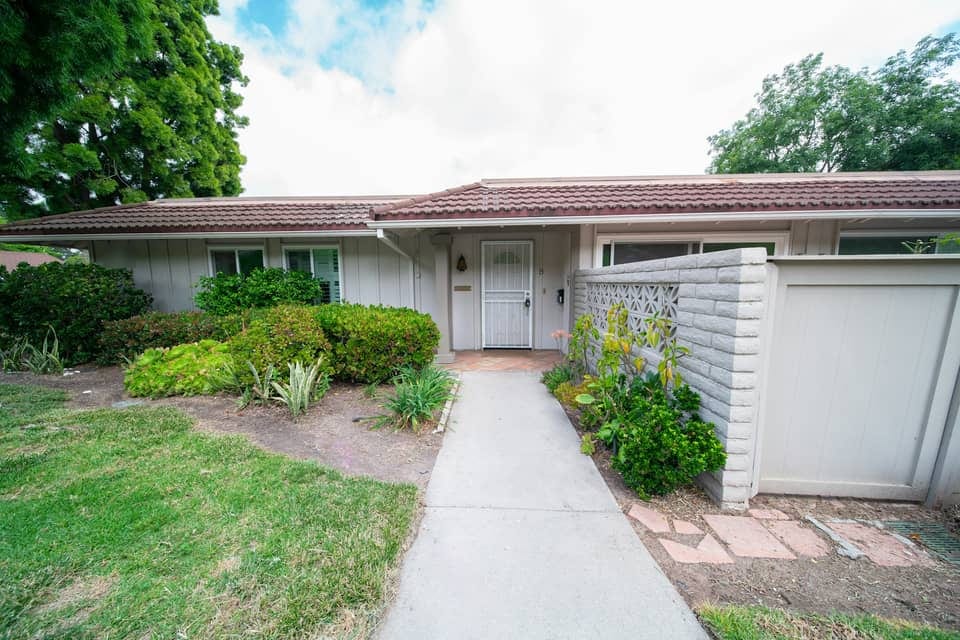 A single-storey ranch house with a low-pitched roof, a front lawn and a concrete path to the door